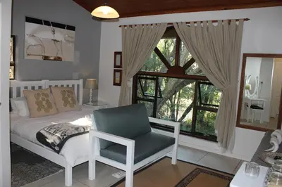 a bedroom with a bed and a chair and a window at The Sabie Town House Guest Lodge in Sabie