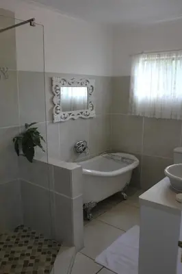 a bathroom with a bath tub and a sink at The Sabie Town House Guest Lodge in Sabie