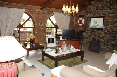 a living room with a couch and a tv at The Sabie Town House Guest Lodge in Sabie