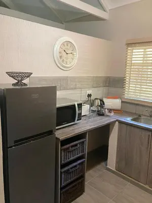 a kitchen with a refrigerator and a clock on the wall at Tranquil Nest in Hazyview