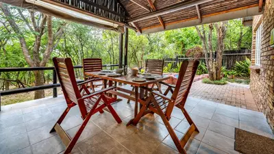 a wooden table and chairs on a patio at Tranquil Nest in Hazyview