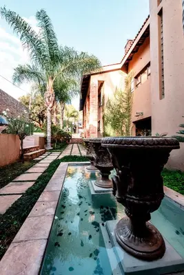 a fountain in front of a building with palm trees at Château La Mer Exclusive Guesthouse & Spa in Hartbeespoort