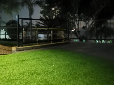 a park with a fence and green grass at night at Kosmos, Hartbeespoort in Hartbeespoort