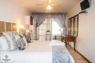 a bedroom with a large bed with a ceiling fan at Snooze-A-Lot Guesthouse in Secunda