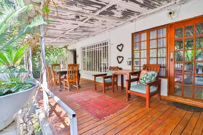 a room with a table and chairs on a wooden deck at Snooze-A-Lot Guesthouse in Secunda