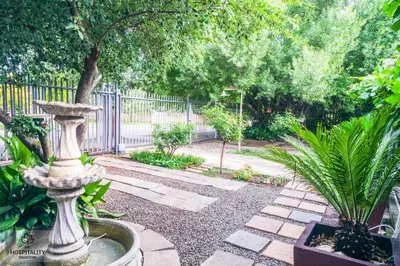 a garden with a stone fountain and a tree at Snooze-A-Lot Guesthouse in Secunda