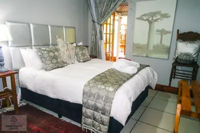a bedroom with a large bed with white sheets and pillows at Snooze-A-Lot Guesthouse in Secunda