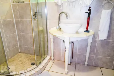 a bathroom with a sink and a shower at Snooze-A-Lot Guesthouse in Secunda