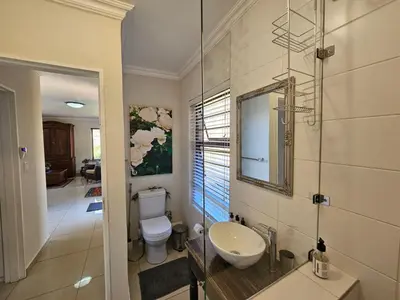 a bathroom with a sink and a toilet and a mirror at Jasmine Guest Cottage in Benoni