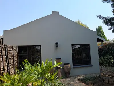 a white house with a fence at Jasmine Guest Cottage in Benoni