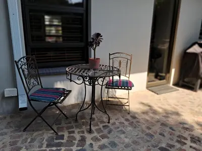 a table with two chairs and a table with a plant on it at Jasmine Guest Cottage in Benoni