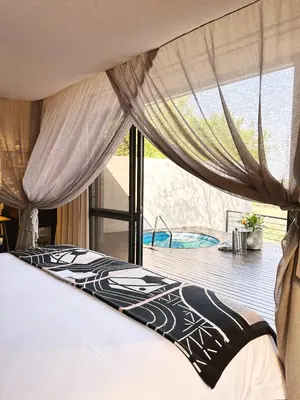 a bedroom with a bed and a view of a pool at Kruger Shalati - Train on The Bridge & Garden Suites in Skukuza