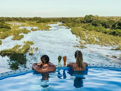 two people in a pool of water in a river at Kruger Shalati - Train on The Bridge & Garden Suites in Skukuza