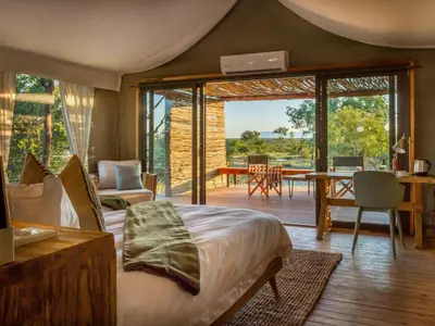 a bedroom with a bed and a living room with a patio at Imagine Africa Luxury Tented Camp in Balule Game Reserve