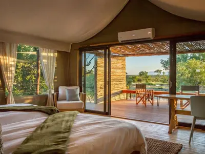 a bedroom with a bed and a view of a deck at Imagine Africa Luxury Tented Camp in Balule Game Reserve