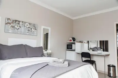 a white bedroom with a bed and a kitchen at Dara on Schabort street in Trichardt