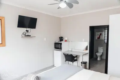 a white bedroom with a bed and a desk and a sink at Dara on Schabort street in Trichardt