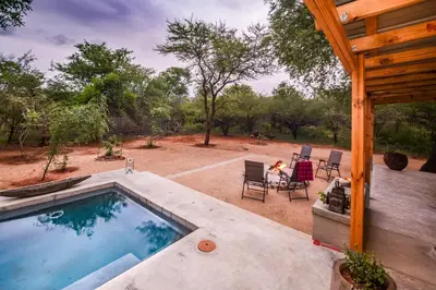 a backyard with a swimming pool and a table and chairs at Khiza Bush Retreat in Hoedspruit
