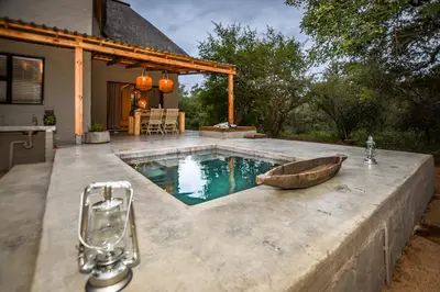 a swimming pool with a wooden boat on a patio at Khiza Bush Retreat in Hoedspruit