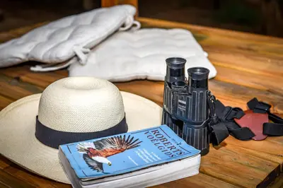 a hat and a book and a bottle on a table at Khiza Bush Retreat in Hoedspruit