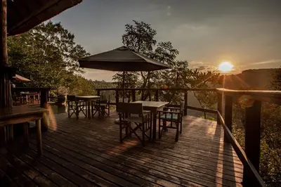 a wooden deck with tables and chairs and an umbrella at Tanamera Lodge in Hazyview
