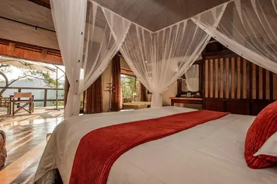 a bedroom with a large bed with white curtains at Tanamera Lodge in Hazyview