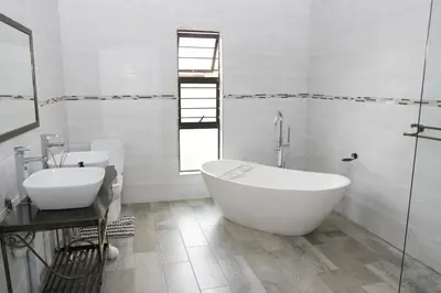 a white bathroom with two sinks and a bath tub at Charis View Guest House in Belfast