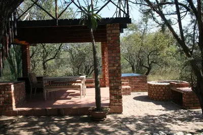 a pavilion with a table and a bench on a patio at Bushbaby Eden in Marloth Park