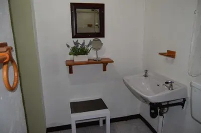a bathroom with a sink and a mirror and a stool at Bushbaby Eden in Marloth Park
