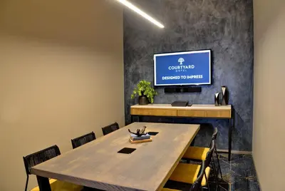 a conference room with a table and a tv on a wall at Courtyard Hotel Waterfall City in Midrand