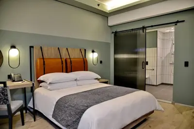 a bedroom with a large bed and a bathroom at Courtyard Hotel Waterfall City in Midrand