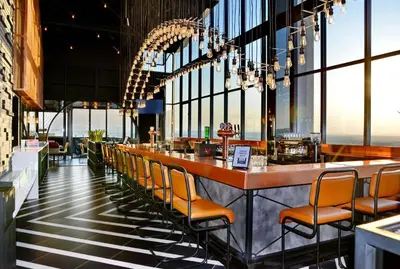 a restaurant with a bar with chairs and windows at Courtyard Hotel Waterfall City in Midrand