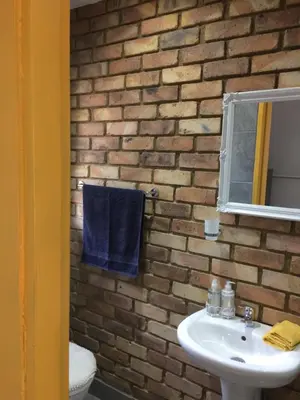 a bathroom with a white sink and a brick wall at B&B 464 on 22nd Ave in Pretoria