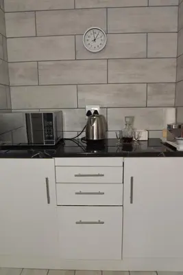 a kitchen counter with a clock on a wall at B&B 464 on 22nd Ave in Pretoria
