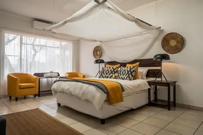 a bedroom with a large bed and a chair at Tshukudu Game Lodge in Hoedspruit