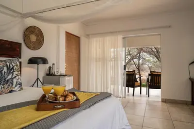 a bedroom with a bed with a tray of food on it at Tshukudu Game Lodge in Hoedspruit