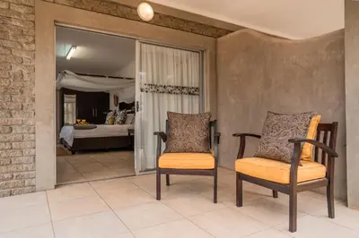 two chairs sitting in a room with a bedroom at Tshukudu Game Lodge in Hoedspruit
