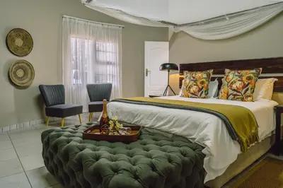 a bedroom with a large bed with a green ottoman at Tshukudu Game Lodge in Hoedspruit
