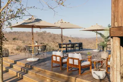 a wooden deck with tables and chairs and umbrellas at Isambane Camp in Balule Game Reserve