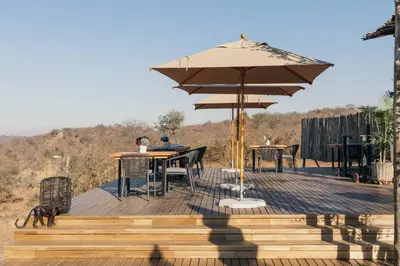 a wooden deck with a table and an umbrella at Isambane Camp in Balule Game Reserve