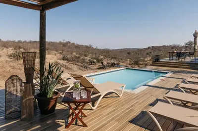 a deck with a pool and chairs and a table at Isambane Camp in Balule Game Reserve