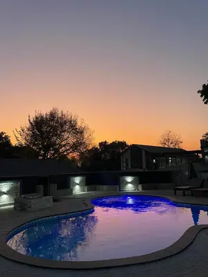 a large swimming pool with a sunset in the background at Summerwood Contractors Home in Nelspruit