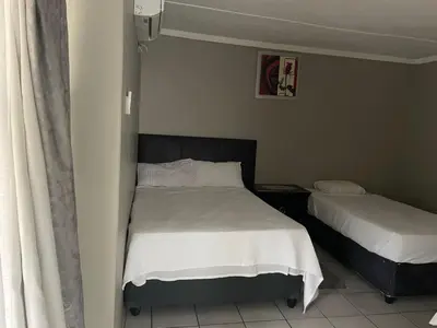a bedroom with two beds with white sheets at Summerwood Contractors Home in Nelspruit