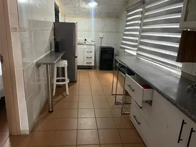 a kitchen with a black refrigerator and white cabinets at Summerwood Contractors Home in Nelspruit