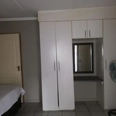 a room with white cabinets and a bed and a window at Summerwood Contractors Home in Nelspruit