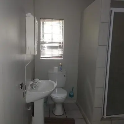 a bathroom with a toilet and a sink and a window at Summerwood Contractors Home in Nelspruit