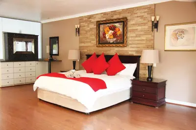 a bedroom with a large bed with red pillows at African BnB - The Boutique Experience in Benoni