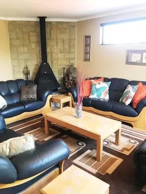 a living room with black leather couches and a table at African BnB - The Boutique Experience in Benoni