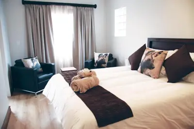 a teddy bear sitting on a bed with two chairs at African BnB - The Boutique Experience in Benoni