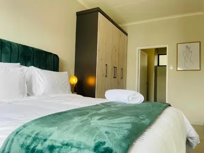 a bedroom with a large bed and a cabinet at Mikeys place On New: 2bed2bath no.1 with Free WiFiNetflix in Midrand